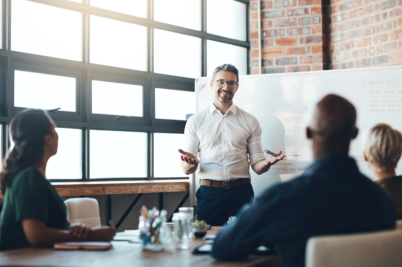 Presenter at a whiteboard speaking to colleagues in an office meeting